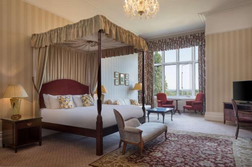 埃文河畔斯特拉特福The Welcombe Golf & Spa Hotel的一间带天蓬床的卧室和一间客厅