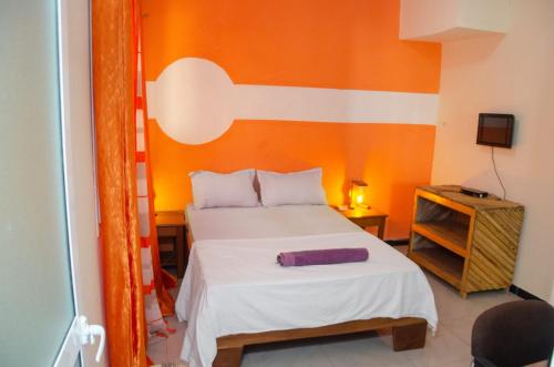 济金绍尔Kër Adja的一间卧室配有一张橙色墙壁的床