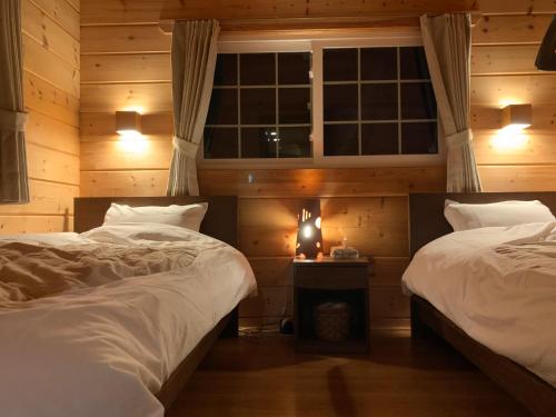 安昙野市安曇野遊人Ｃ.Ｌ.Ｊ.クラブ的一间卧室设有两张床和窗户。