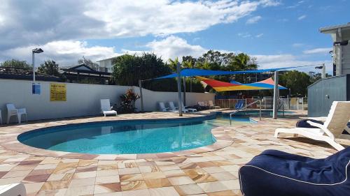亚历山德拉岬角亚历克斯海滩小屋和观光园酒店的庭院内一个带椅子和遮阳伞的游泳池
