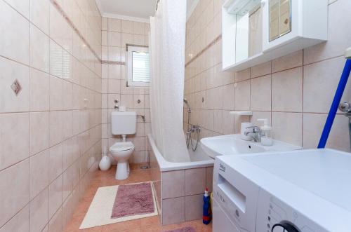 洛帕Apartments Marija P Lopar的浴室配有盥洗盆、卫生间和浴缸。