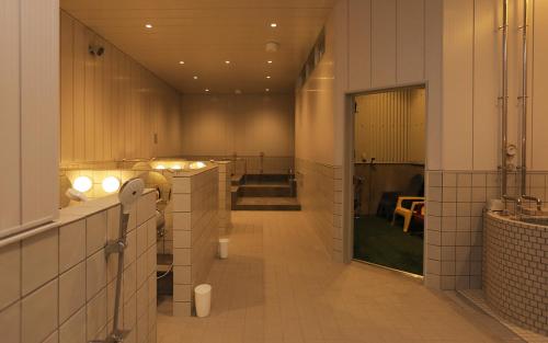 盛冈Hotel Mazarium的浴室设有白色瓷砖墙壁和长长的走廊