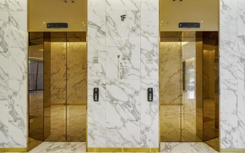 釜山Busan Myeongji Ciel Ocean Hotel的大堂设有四部电梯,配有大理石墙壁和镜子