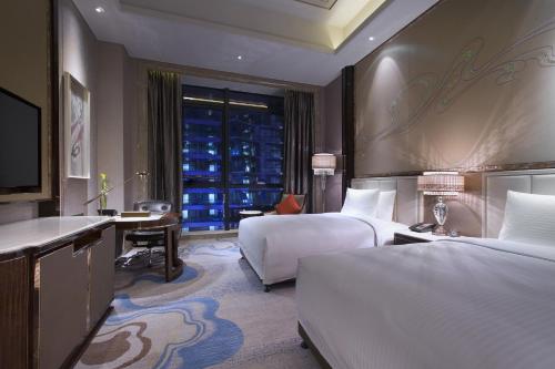 兰州兰州富力万达文华酒店的酒店客房设有两张床、一张书桌和一个窗户。