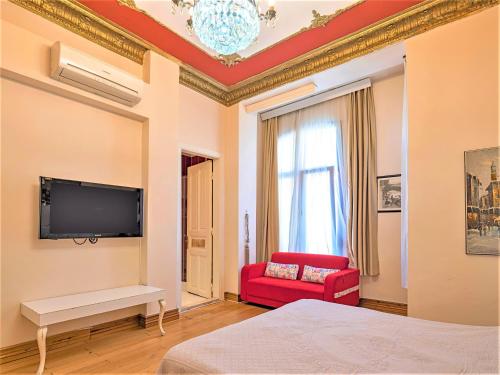 伊斯坦布尔Ragip Pasha Apartments的卧室设有壁挂式电视和红色椅子