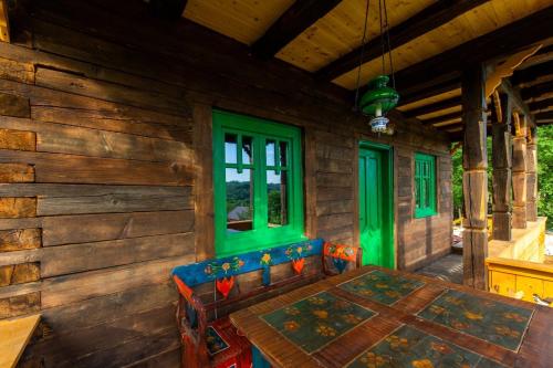 BerteaLa sat - Mândră Ioană的小木屋的门廊,配有桌子和绿色窗户