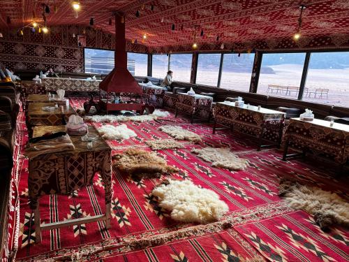 瓦迪拉姆Desert Bird Camp的红色地毯上的带桌椅的用餐室
