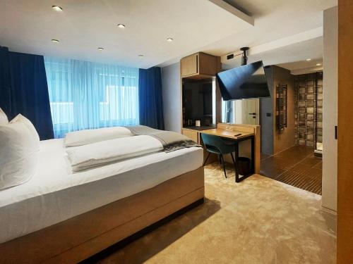 罗伊特林根DORMERO Hotel Reutlingen的一间卧室配有一张床、一张书桌和一台电视
