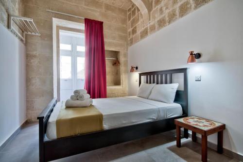 瓦莱塔Vallettastay Old Lodge Apartment 4的一间卧室配有一张带红色窗帘的大床