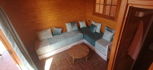 本苏莱曼Ferme Sacrée Nature的木制客房内的一张小床,配有枕头