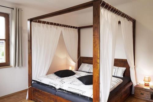 Gemeinde AichhaldenSchwarzwaldhaus24 - Ferienhaus mit Sauna, Whirlpool und Kamin的卧室配有带白色窗帘的天蓬床