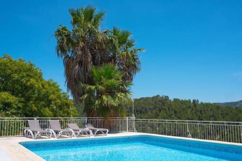 Llano de GorraVilla Montgrau的一个带椅子的游泳池,并种植了棕榈树