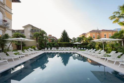 加尔达湖滨自由大酒店的一个带白色椅子和遮阳伞的游泳池