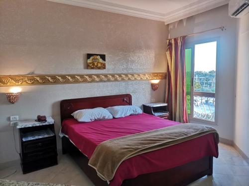 赫尔格达金玫瑰酒店的一间卧室设有一张红色大床和窗户