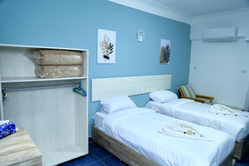 赫尔格达Lamera Hotel的蓝色墙壁客房的两张床