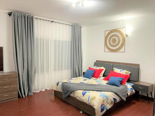 塔那那利佛Appartements - Le Paradisier Ambatobe的一间卧室配有蓝色和红色枕头的床