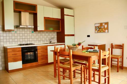 皮诺港Casa vacanza "Maestrale "的厨房配有木桌、椅子和水槽