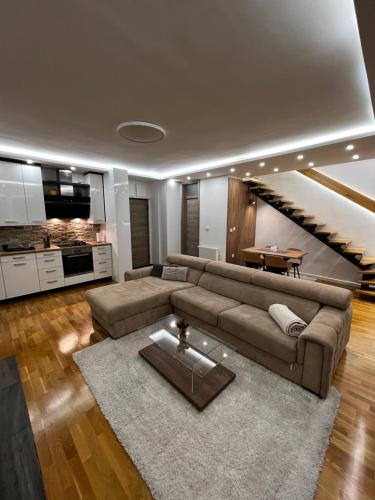 别拉什尼察Inverno Apartments Bjelašnica的客厅设有棕色的沙发和楼梯。