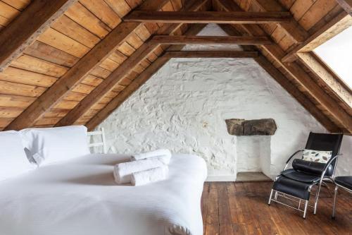 凯里肯Isle of Skye Cottage的卧室配有白色的床和石墙