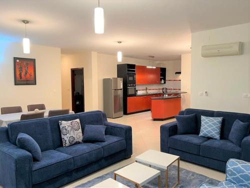 塔那那利佛Appartements - Le Paradisier Ambatobe的一间带2张蓝色沙发的客厅和一间厨房