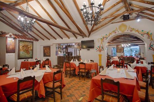 库斯科Munay Wasi Inn的餐厅设有红色的桌椅和电视。