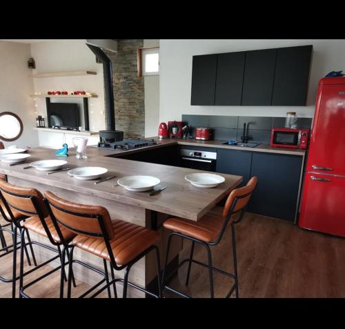 布雷斯特A quelques pas du moulin blanc的厨房配有带椅子的木桌和红色冰箱。
