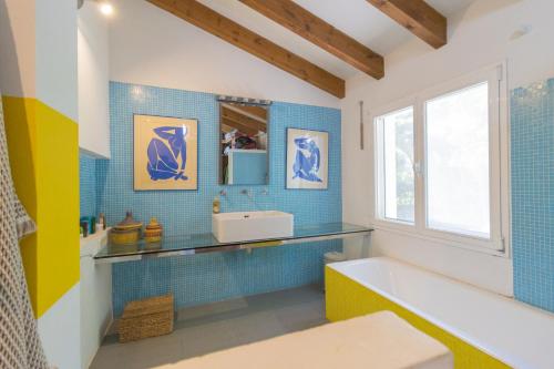哈维亚Casa Algarrobo的浴室铺有蓝色瓷砖,配有浴缸和水槽。