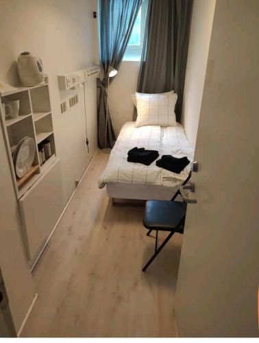 哥本哈根Bjergvænget 16, 2400 København的小房间设有一张床和一把椅子