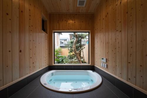 金泽Kenrokutei Oyado的一个带窗户的客房内的按摩浴缸