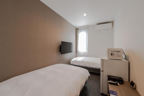SakaiHOTEL R9 The Yard Sakai的酒店客房设有两张床和电视。