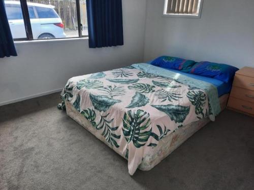 帕帕莫阿Papamoa Holiday Home的一间卧室配有一张带鲜花毯子的床