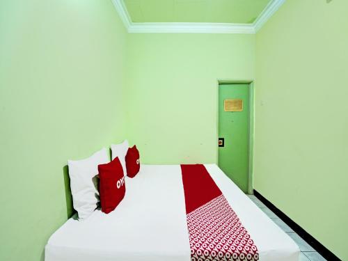 RamekasanOYO 2708 Hotel Kemuning Syariah的卧室配有带红色枕头的白色床