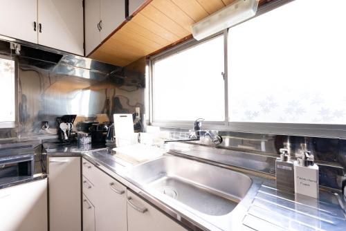 箱根樹蘭蕉 箱根仙石原 - JYURANSHO Hakonesengokuhara的厨房设有水槽和窗户。