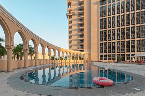 多哈Al Gassar Resort的一座建有建筑物的城市游泳池上的桥梁
