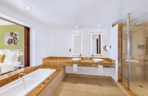 潘托皮芒Victoria Beachcomber Resort & Spa的浴室配有2个盥洗盆、浴缸和淋浴。