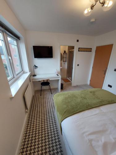 曼彻斯特bankwellstreet的一间卧室配有一张床、一张书桌和一台电视