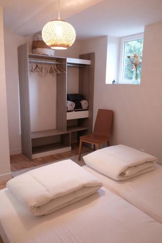 雷克图尔Gîte le petit écolier的一间卧室设有两张床、一把椅子和一个窗户。
