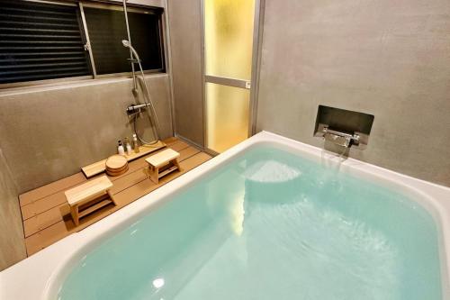 青梅市加美屋リゾート奥多摩 テラス＆風呂的一间带大型蓝色浴缸及窗户的浴室