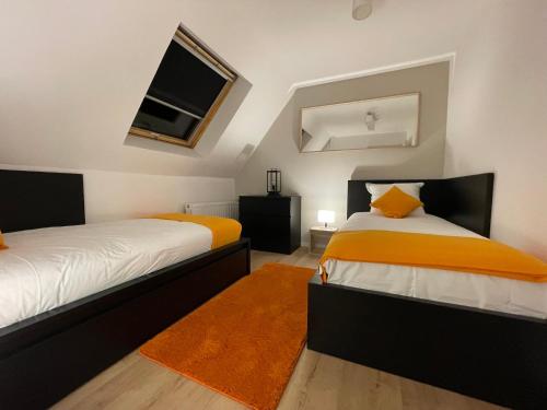 奥内姆Le 6B的一间卧室配有两张带橙色和白色床单的床