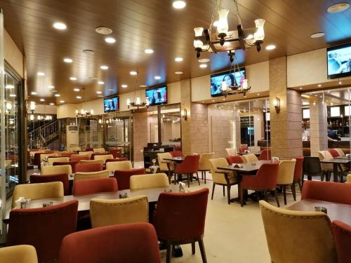 扎赫勒La Place Hotel的一间带桌椅和电视的餐厅