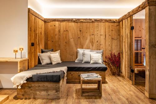 布鲁尼科Bellevue Bruneck - Suites & Lofts的一间卧室设有木墙、一张床和一张桌子