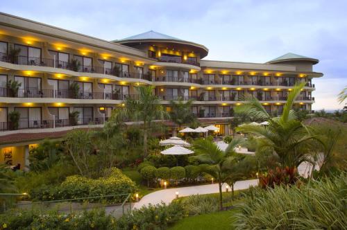福尔图纳The Royal Corin Thermal Water Spa & Resort - Adults Only的酒店设有带遮阳伞和棕榈树的庭院。