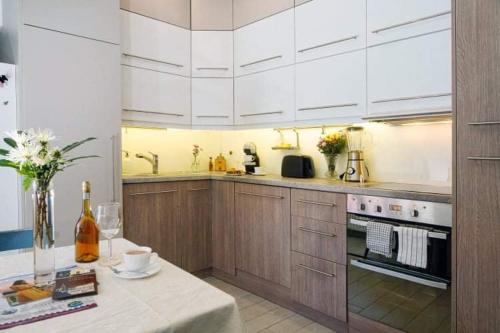 韦莱姆Velem Spirit Apartment的厨房配有白色橱柜和1张带1瓶葡萄酒的桌子