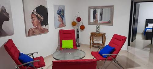里奥阿查La Marina -Apartamentos frente al mar的一间设有红色椅子和玻璃桌的房间