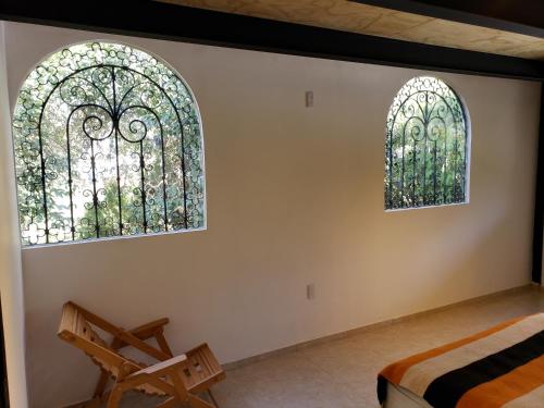 特基斯基亚潘VILLA COLONIAL的两扇窗户,配有一张床和椅子