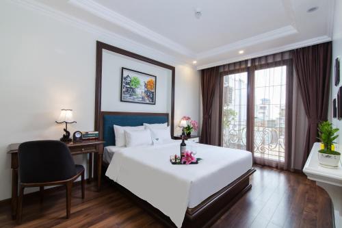河内Hanoi Calista Hotel的配有一张床、一张书桌和一扇窗户的酒店客房
