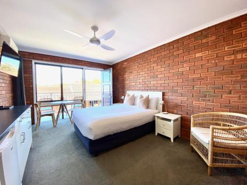 梅林布拉鹈鹕汽车旅馆的一间卧室设有一张床和砖墙