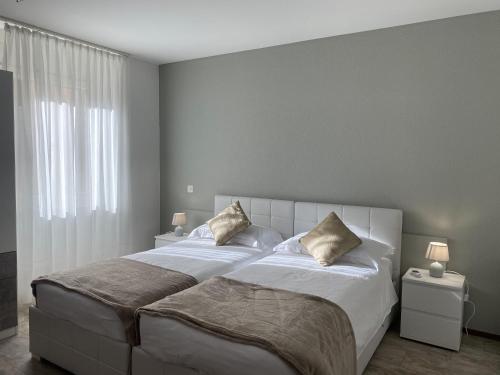 Roveredo车站旅馆的卧室配有一张带两个枕头的大白色床