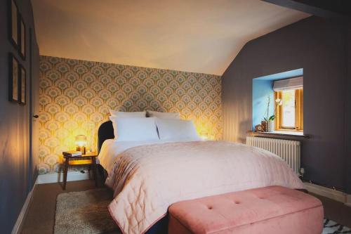 威尔斯浦River Cottage, a luxurious and cosy riverside cottage for two的一间卧室配有一张大床和一张粉红色的长凳