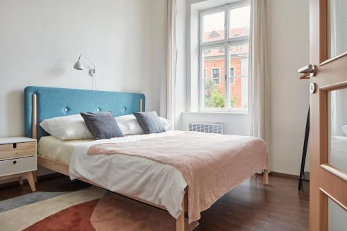 布拉格Modern Flat in Old Town by Prague Days的一间卧室配有一张带蓝色床头板的床和窗户